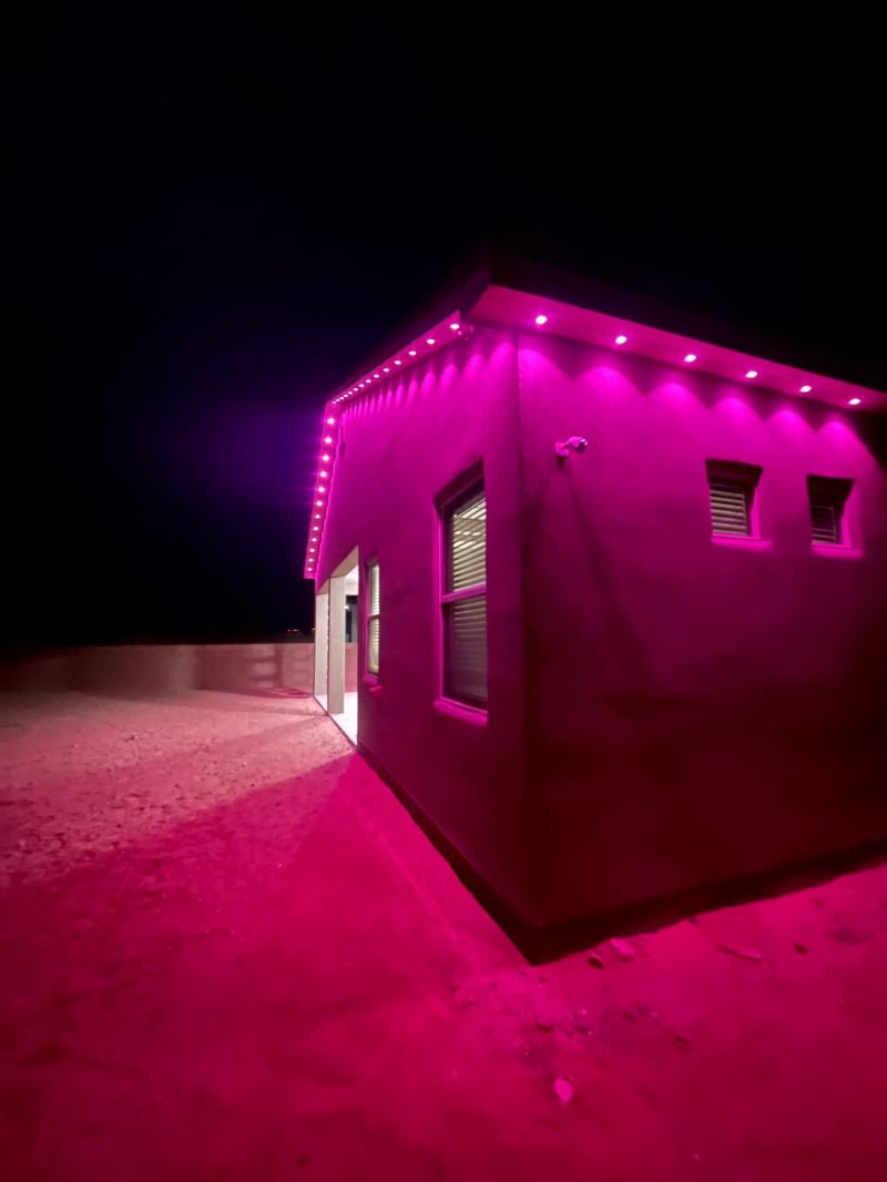 Permanent lighting set to a pink scene along the roofline and eaves of a home
