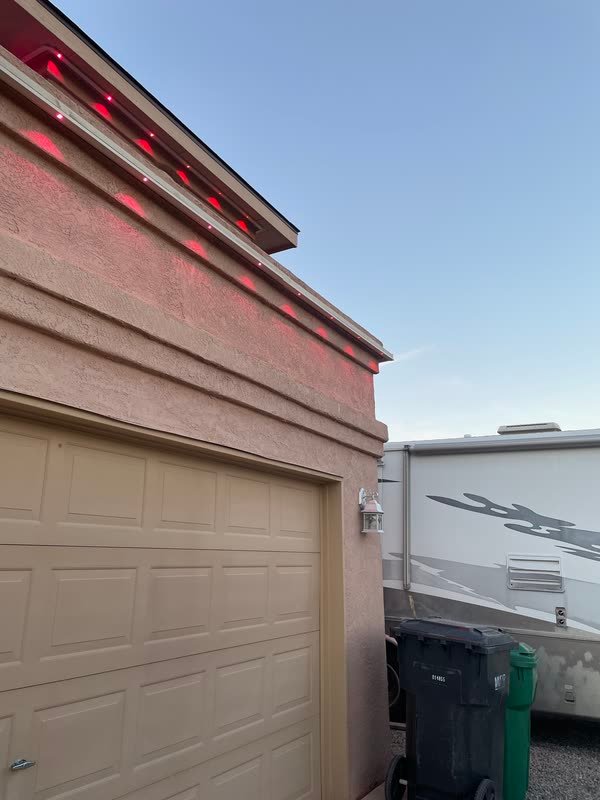 Permanent lighting set to red along the stepped parapet of an Albuquerque home at dusk, with the mounting channel still visible in the light