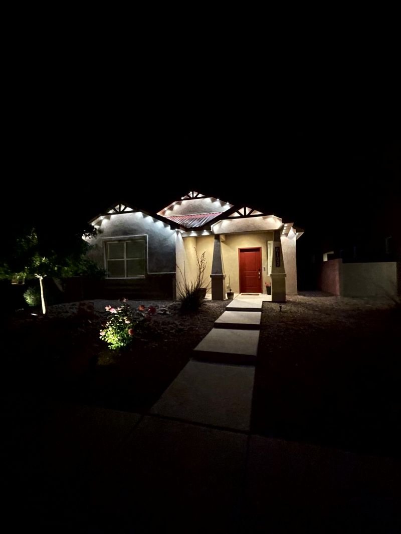 Warm white permanent lighting outlining the facade and entry of a home after dark